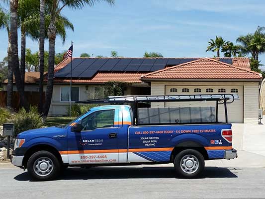SolarTech work truck parked in front of house with solar panel roof installation